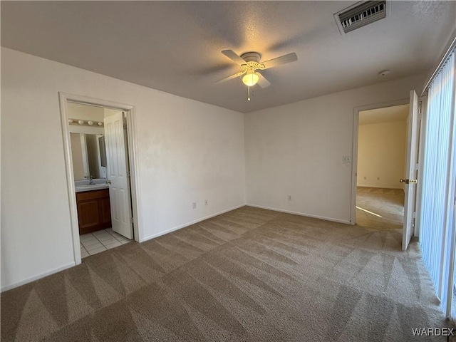 unfurnished bedroom with visible vents, connected bathroom, light carpet, and baseboards