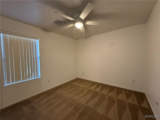 unfurnished room with ceiling fan, dark colored carpet, visible vents, and baseboards