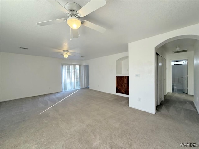 carpeted spare room featuring arched walkways and visible vents