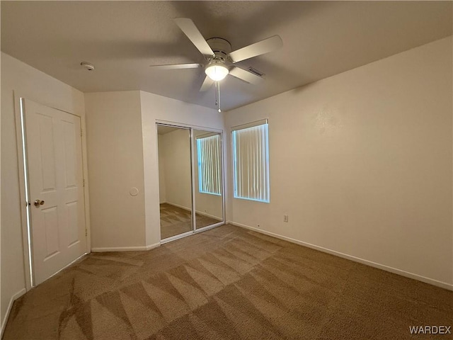 unfurnished bedroom with a closet, carpet flooring, ceiling fan, and baseboards