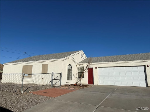 view of front of property with concrete driveway, an attached garage, a gate, fence, and stucco siding