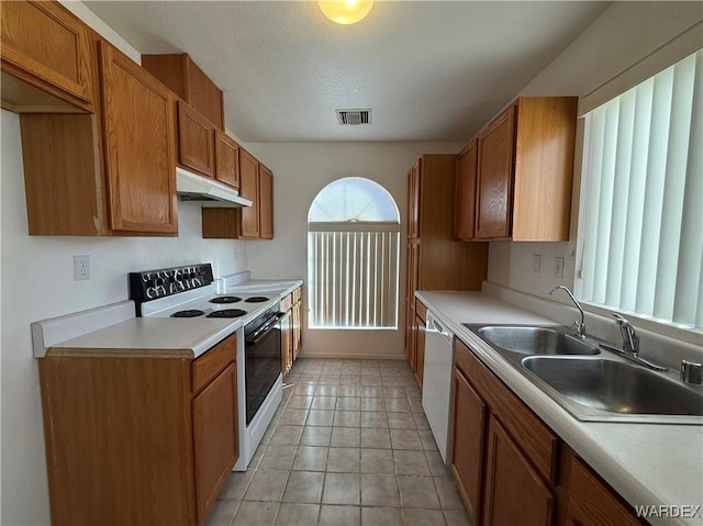 kitchen featuring visible vents, electric range oven, white dishwasher, under cabinet range hood, and a sink