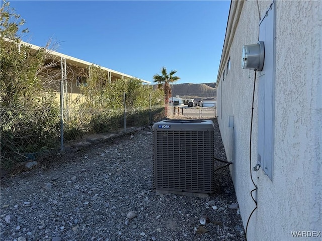 exterior details with central AC, fence, and stucco siding