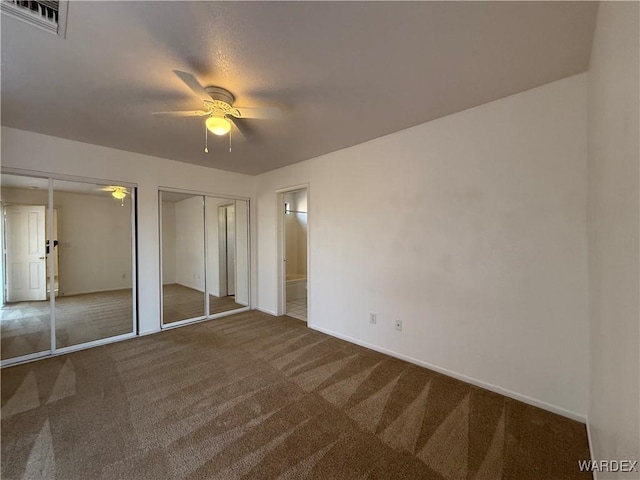 unfurnished bedroom with carpet floors, two closets, visible vents, ensuite bathroom, and a ceiling fan