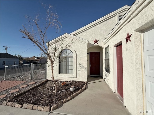 entrance to property with fence, a gate, and stucco siding