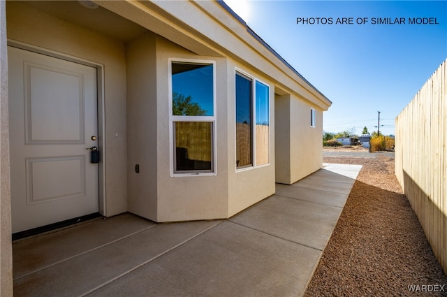 view of side of property with a patio area, fence, and stucco siding