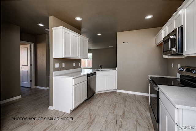 kitchen featuring stainless steel appliances, recessed lighting, light countertops, white cabinets, and a sink