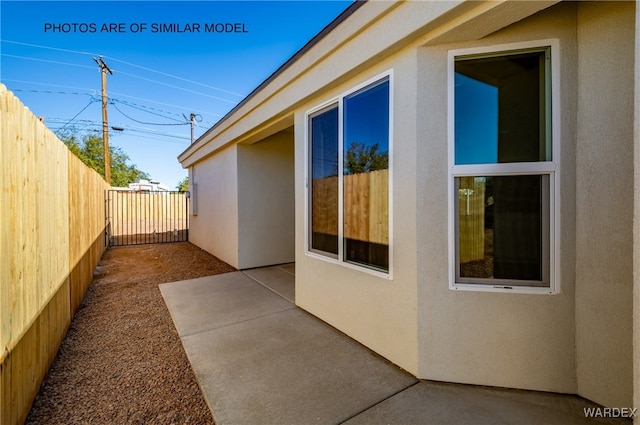 view of side of home featuring a patio area, fence, and stucco siding