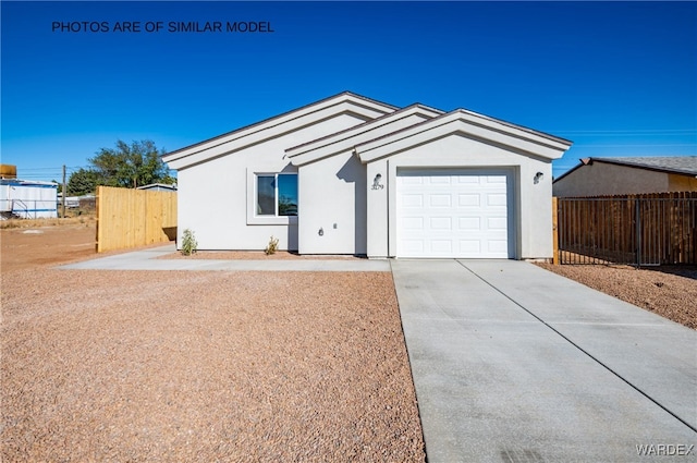 ranch-style house featuring driveway, an attached garage, fence, and stucco siding