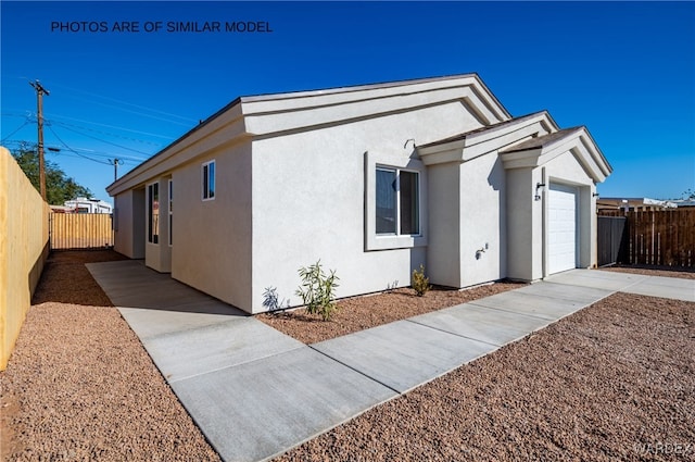 view of side of property with an attached garage, fence, and stucco siding