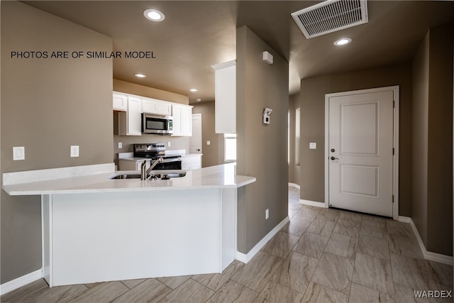 kitchen with stainless steel appliances, visible vents, white cabinets, a sink, and a peninsula