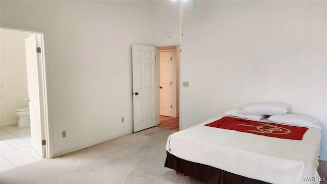 bedroom with light tile patterned floors, light carpet, and ensuite bathroom