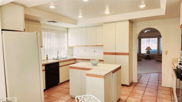 kitchen featuring dishwasher, light countertops, a sink, and freestanding refrigerator