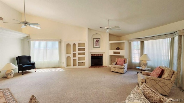 living room featuring built in shelves, a fireplace, light carpet, ceiling fan, and high vaulted ceiling