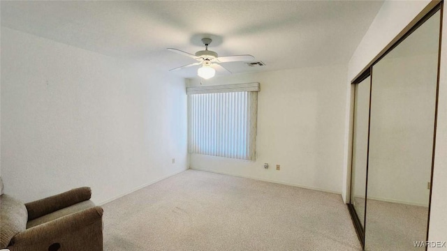 unfurnished bedroom featuring a ceiling fan, a closet, visible vents, and light carpet