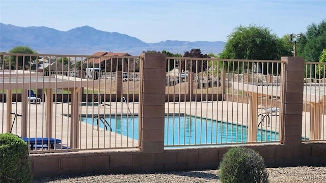 pool featuring a patio, fence, and a mountain view