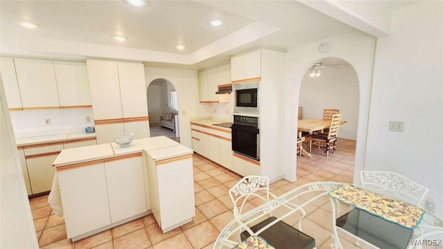 kitchen featuring arched walkways, white cabinets, black oven, and a kitchen island