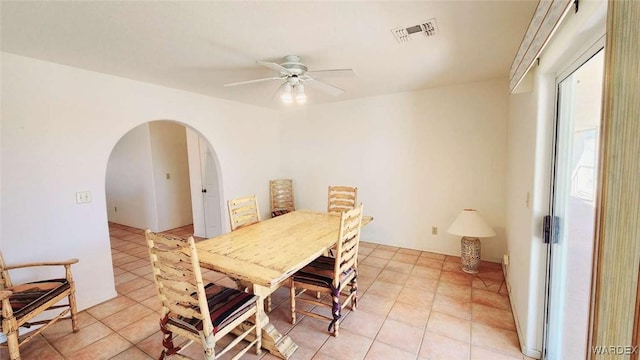 dining area featuring arched walkways, visible vents, ceiling fan, and light tile patterned flooring