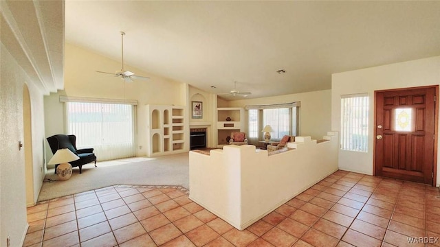 interior space featuring built in features, a ceiling fan, a fireplace, and light tile patterned floors