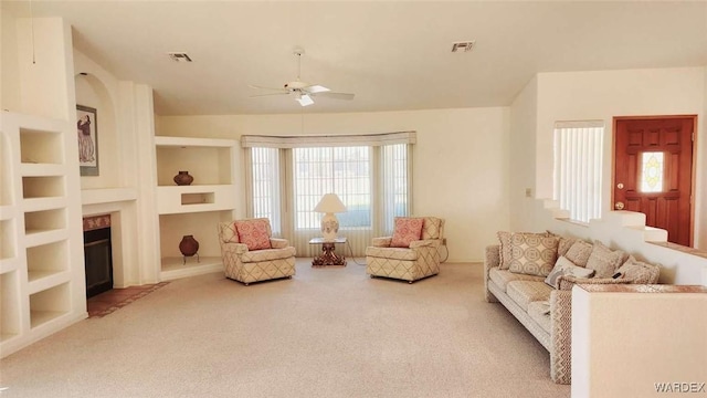 living room featuring light carpet, built in shelves, plenty of natural light, and visible vents