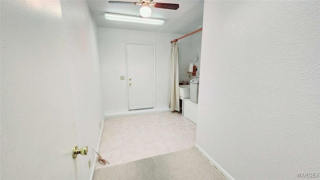 hall featuring light carpet, a textured wall, and baseboards