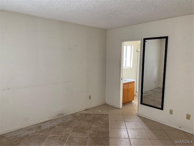 unfurnished room with a textured ceiling and light tile patterned floors