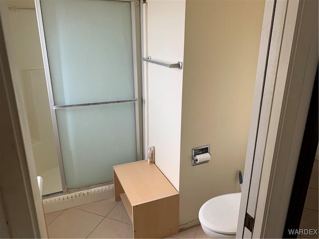 full bath featuring toilet, a stall shower, and tile patterned flooring