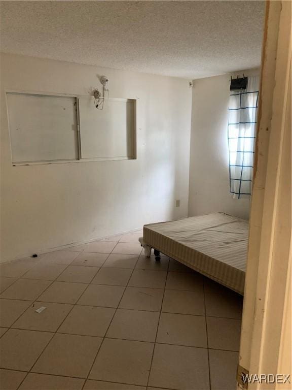 unfurnished bedroom with a textured ceiling and tile patterned flooring