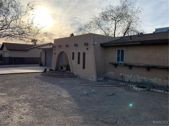 adobe home featuring a garage, concrete driveway, and stucco siding