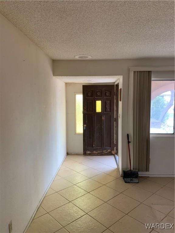 entrance foyer with a textured ceiling and light tile patterned floors