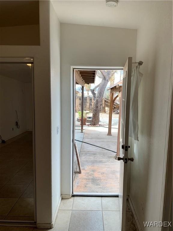 doorway featuring light tile patterned floors and baseboards