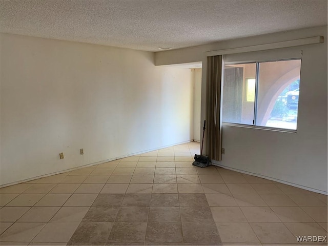 unfurnished room with light tile patterned floors and a textured ceiling