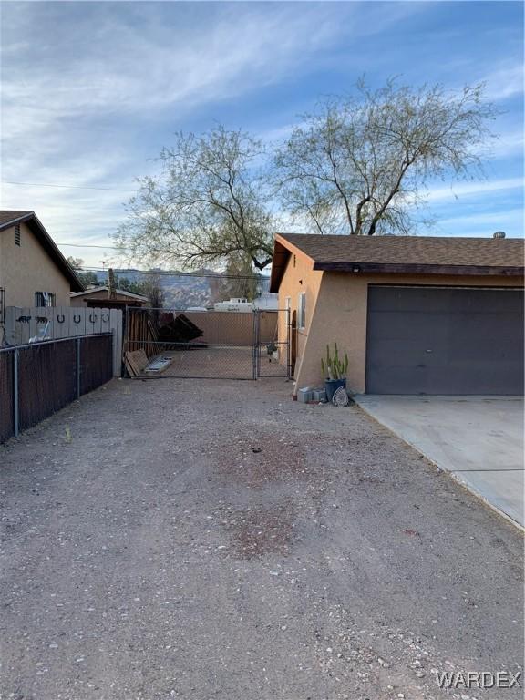 view of side of property with a garage, fence, a gate, and stucco siding