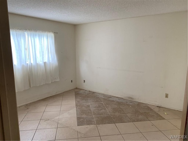 empty room featuring light tile patterned floors and a textured ceiling