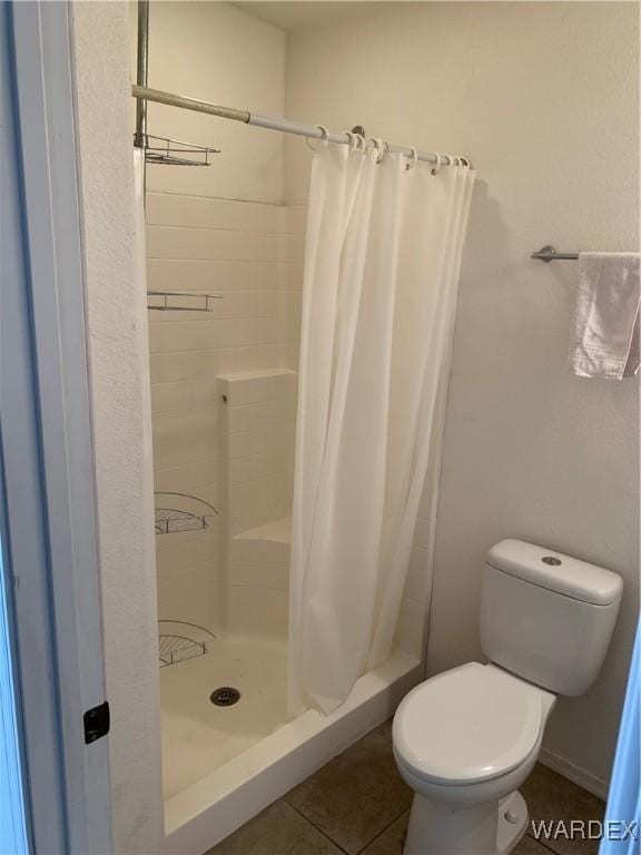 full bath featuring tile patterned flooring, a shower stall, toilet, and baseboards