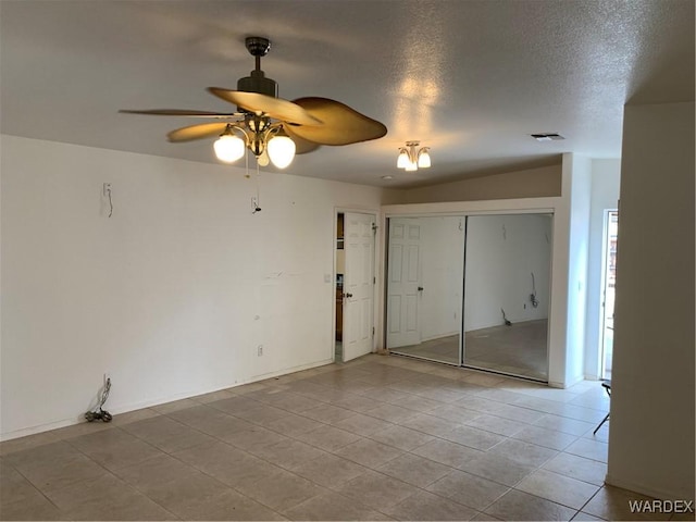 empty room featuring a ceiling fan, visible vents, light tile patterned flooring, and a textured ceiling