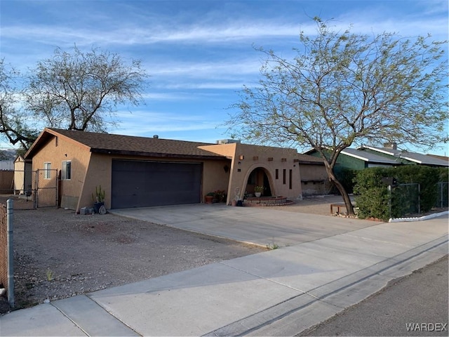 southwest-style home with a garage, fence, driveway, a gate, and stucco siding