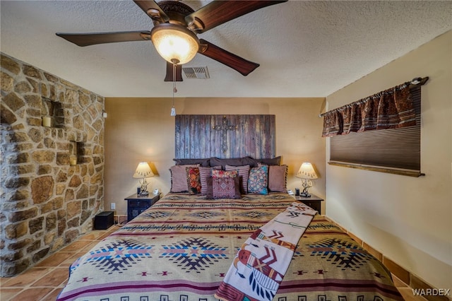 bedroom with tile patterned flooring, visible vents, ceiling fan, and a textured ceiling