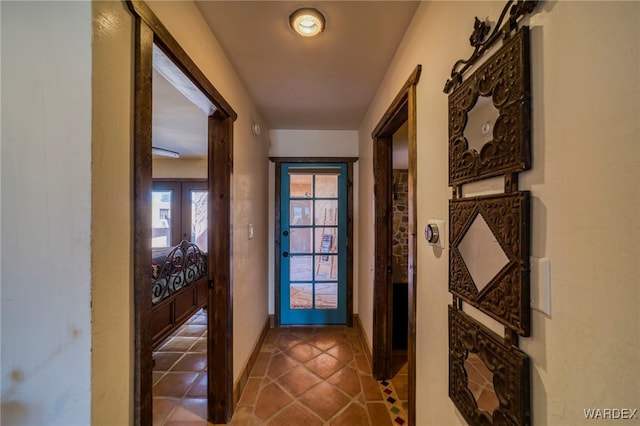 doorway with french doors, baseboards, and tile patterned floors