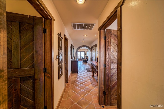 hall featuring visible vents, arched walkways, and tile patterned floors