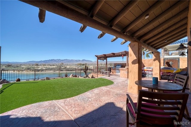 view of patio / terrace with exterior kitchen, a fenced backyard, a mountain view, and a pergola