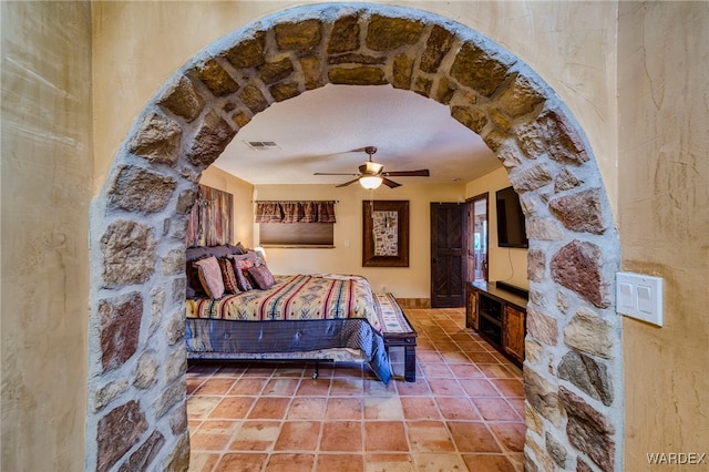 bedroom featuring arched walkways, visible vents, and a ceiling fan