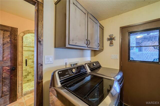 laundry area featuring washer and dryer, cabinet space, and a textured ceiling