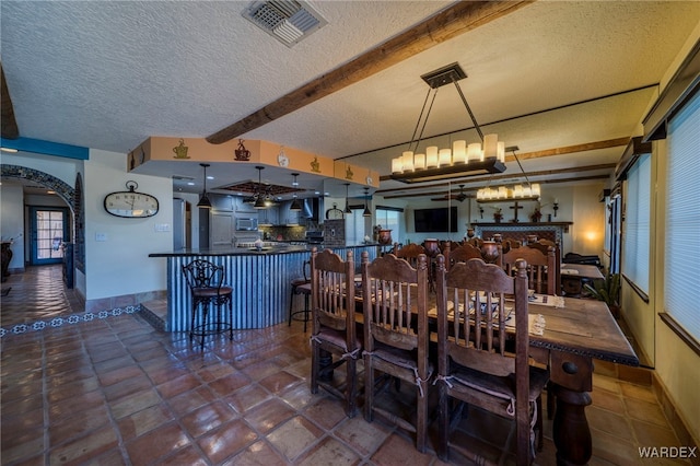 dining space with baseboards, visible vents, arched walkways, a textured ceiling, and beam ceiling