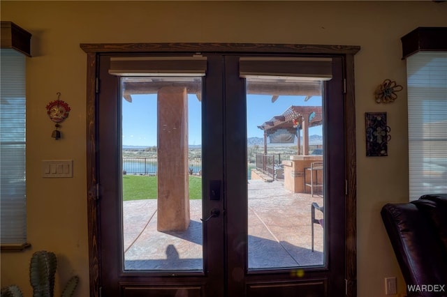 doorway to outside featuring a water view, a wealth of natural light, and french doors