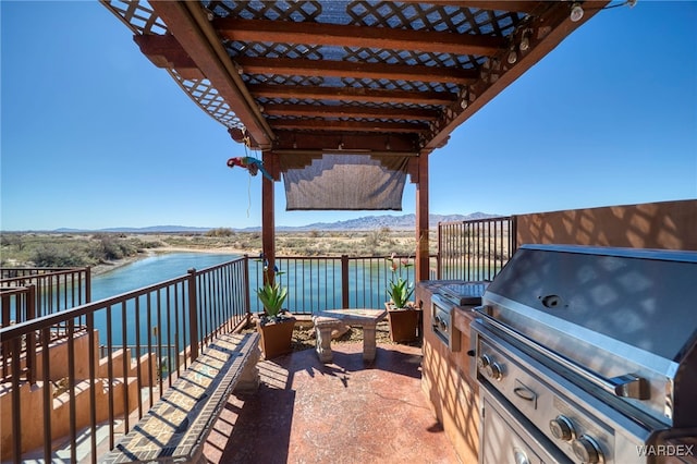 view of patio / terrace featuring exterior kitchen, area for grilling, and a water and mountain view