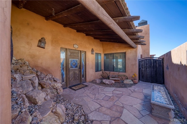 view of exterior entry featuring a gate, a patio area, and fence