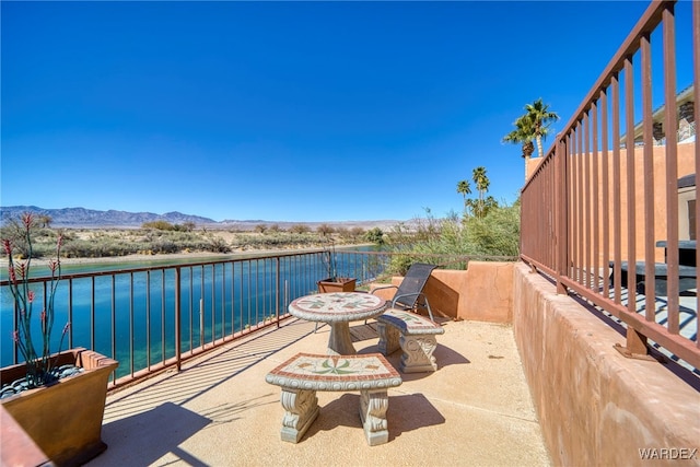 view of patio featuring a balcony and a water and mountain view