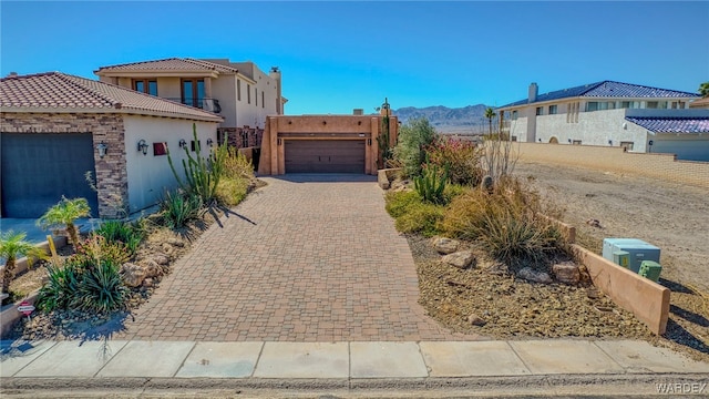 view of front facade featuring a garage, decorative driveway, a mountain view, and stucco siding