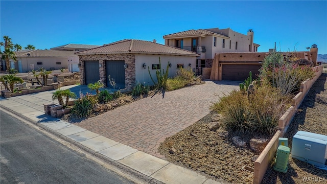 view of front of home featuring stone siding, a tile roof, decorative driveway, and stucco siding